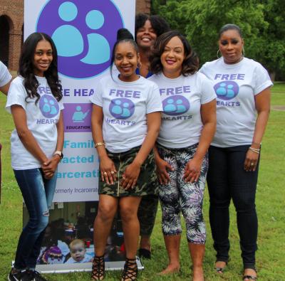A group of women wearing Free Hearts t-shirts posing in front of a Free Hearts sign