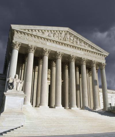 The front of the Supreme Court building with a stormy sky behind it.